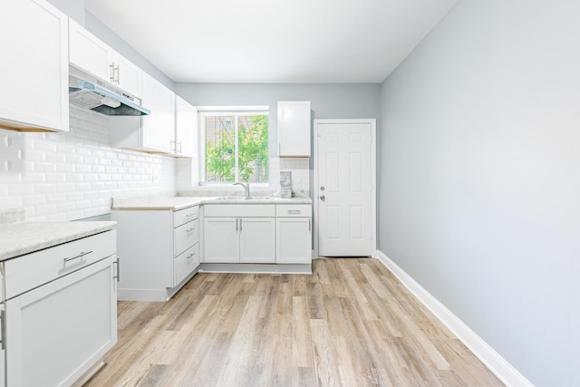1310 E 72nd St, Chicago, IL 60619 - kitchen with under cabinet range hood, light wood-type flooring, tasteful backsplash, and light countertops