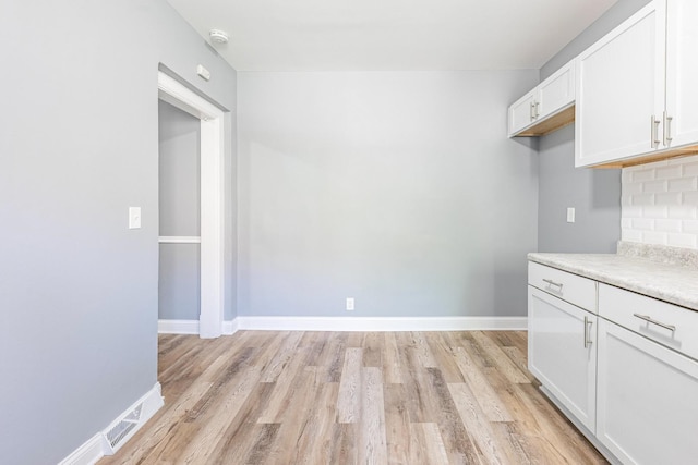 1310 E 72nd St, Chicago, IL 60619 - kitchen featuring light wood-type flooring, white cabinetry, light countertops, and decorative backsplash