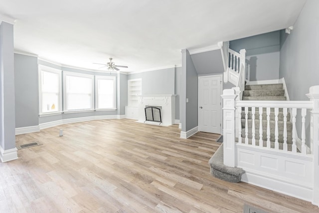 1310 E 72nd St, Chicago, IL 60619 - unfurnished living room featuring a ceiling fan, crown molding, stairs, light wood-type flooring, and a fireplace with flush hearth
