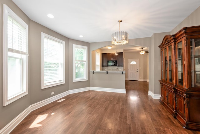 12300 Maple Ave, Blue Island, IL 60406 - kitchen featuring black microwave, dark wood-style flooring, light countertops, a peninsula, and arched walkways