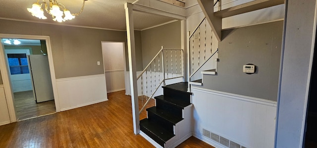 24 Mulberry St, Savanna, IL 61074 - staircase featuring wood finished floors, ornamental molding, wainscoting, and a chandelier
