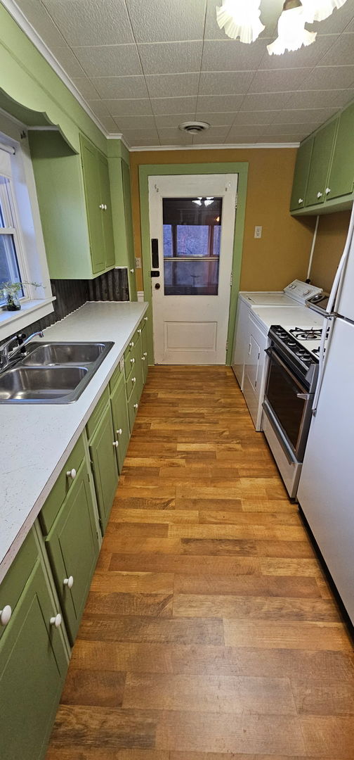 24 Mulberry St, Savanna, IL 61074 - kitchen featuring green cabinets, stainless steel range with gas stovetop, light countertops, light wood finished floors, and crown molding