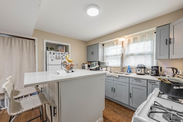 4918 S Luna Ave, Chicago, IL 60638 - kitchen featuring gray cabinetry, freestanding refrigerator, a breakfast bar area, wood finished floors, and a center island