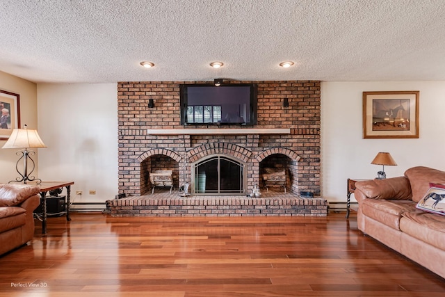 10766 E 7000n Rd, Grant Park, IL 60940 - living area with a textured ceiling, a brick fireplace, a baseboard heating unit, and wood finished floors