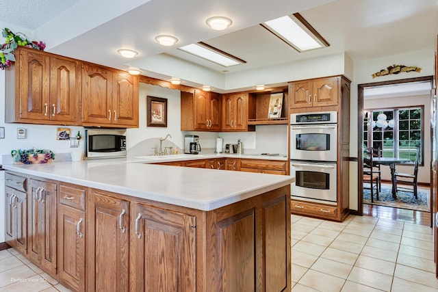 10766 E 7000n Rd, Grant Park, IL 60940 - kitchen with appliances with stainless steel finishes, brown cabinetry, open shelves, light tile patterned floors, and a peninsula
