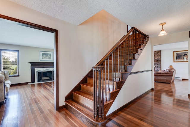 10766 E 7000n Rd, Grant Park, IL 60940 - staircase with hardwood / wood-style floors, a textured ceiling, a fireplace, and baseboard heating