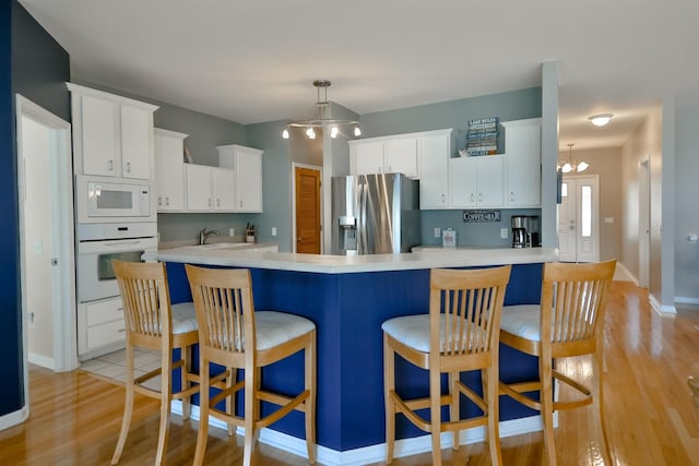 930 Candlewick Dr NE, Poplar Grove, IL 61065 - kitchen featuring white appliances, a chandelier, light countertops, light wood-type flooring, and a kitchen breakfast bar