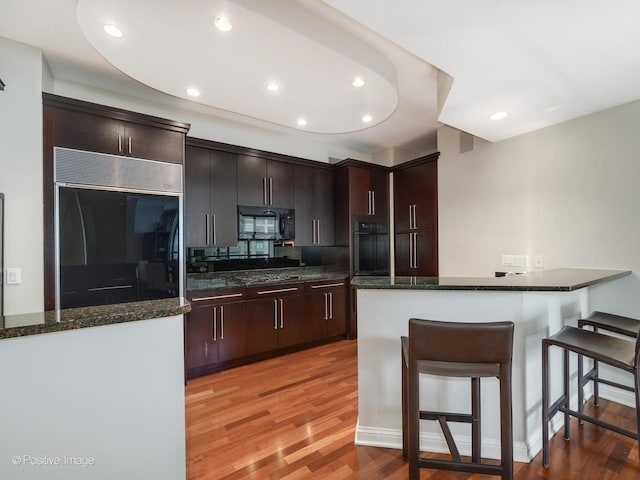 21 E Huron St Unit 1106, Chicago, IL 60611 - kitchen with light wood-style flooring, black appliances, a breakfast bar, recessed lighting, and a peninsula