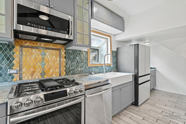 619 N 4th Ave, Maywood, IL 60153 - kitchen featuring stainless steel appliances, gray cabinets, glass insert cabinets, light stone counters, and light wood-style floors
