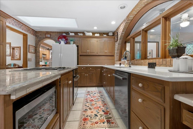 25316 E 1100 N Rd, Downs, IL 61736 - kitchen with appliances with stainless steel finishes, a skylight, light stone countertops, backsplash, and brown cabinetry