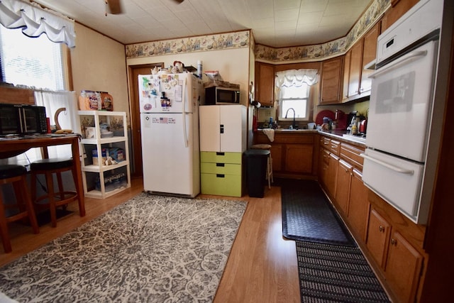 915 W Olive St, Bloomington, IL 61701 - kitchen featuring white appliances, brown cabinets, light wood-style floors, a warming drawer, and crown molding