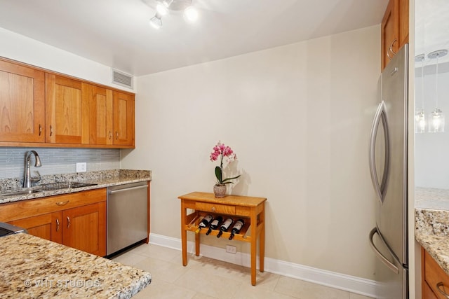 1250 N Dearborn St Unit 11C, Chicago, IL 60610 - kitchen featuring stainless steel appliances, brown cabinets, decorative backsplash, light tile patterned floors, and light stone counters