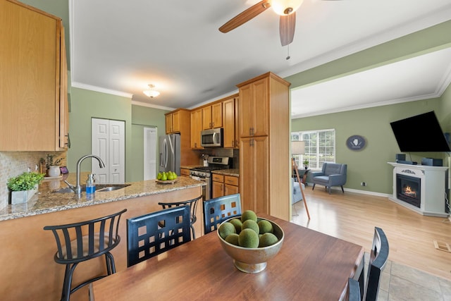 931 Mesa Dr, Elgin, IL 60123 - dining room featuring ornamental molding, light wood-type flooring, ceiling fan, and a lit fireplace