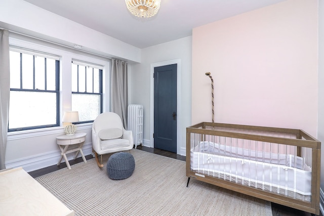 296 N Addison Ave, Elmhurst, IL 60126 - bedroom with radiator heating unit, a chandelier, wood finished floors, and a crib