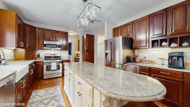 0N488 Baker Dr, Geneva, IL 60134 - kitchen featuring stainless steel appliances, a kitchen island, wood finished floors, light stone countertops, and tasteful backsplash
