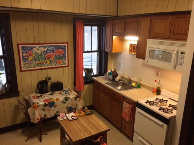 2244 W Augusta Blvd, Chicago, IL 60622 - kitchen with white appliances, light countertops, wood walls, and brown cabinets