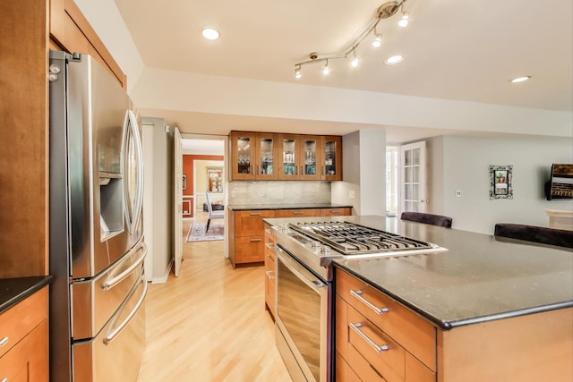 2114 Birchwood Ln, Buffalo Grove, IL 60089 - kitchen featuring stainless steel appliances, light wood-style floors, glass insert cabinets, decorative backsplash, and brown cabinetry