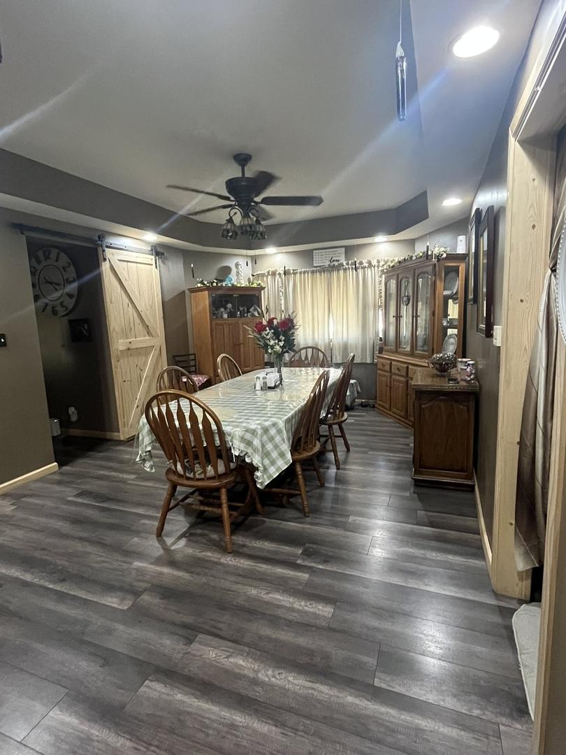 514 E Jackson St, Joliet, IL 60432 - dining room featuring a barn door, a ceiling fan, and dark wood-style floors