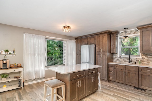 9049 Barberry Ln, Hickory Hills, IL 60457 - kitchen featuring freestanding refrigerator, light wood-style flooring, decorative backsplash, and hanging light fixtures