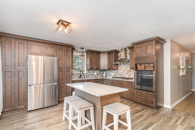 9049 Barberry Ln, Hickory Hills, IL 60457 - kitchen with stainless steel appliances, wall chimney exhaust hood, backsplash, light wood-style floors, and a kitchen breakfast bar