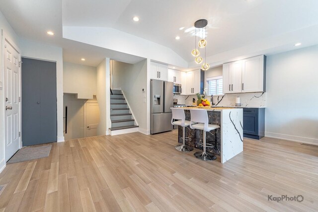 9130 S Greenwood Ave, Chicago, IL 60619 - kitchen with appliances with stainless steel finishes, a kitchen breakfast bar, light countertops, light wood finished floors, and lofted ceiling