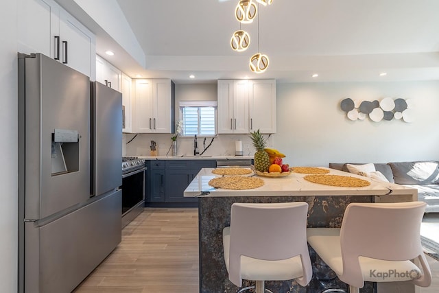 9130 S Greenwood Ave, Chicago, IL 60619 - kitchen with appliances with stainless steel finishes, a breakfast bar, light wood finished floors, recessed lighting, and white cabinets