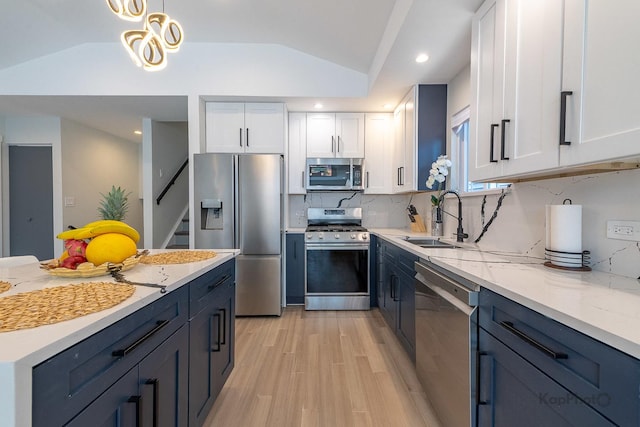 9130 S Greenwood Ave, Chicago, IL 60619 - kitchen with stainless steel appliances, vaulted ceiling, white cabinetry, light wood-style floors, and decorative backsplash