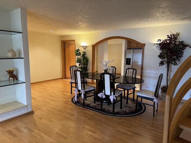 8170 Lake Ridge Dr, Burr Ridge, IL 60527 - dining space featuring a textured wall, a textured ceiling, light wood-type flooring, and arched walkways