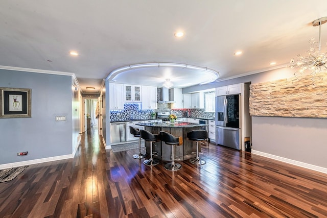 484 Valleyview Dr, Bartlett, IL 60103 - kitchen featuring stainless steel fridge, wall chimney exhaust hood, a breakfast bar area, white cabinetry, and crown molding