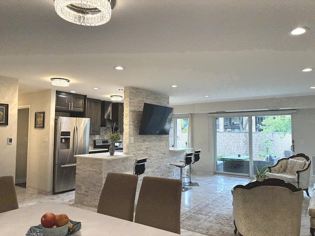 1103 S Hunt Club Dr Unit 125, Mount Prospect, IL 60056 - kitchen featuring stainless steel appliances, light marble finish floors, wall chimney range hood, recessed lighting, and a peninsula