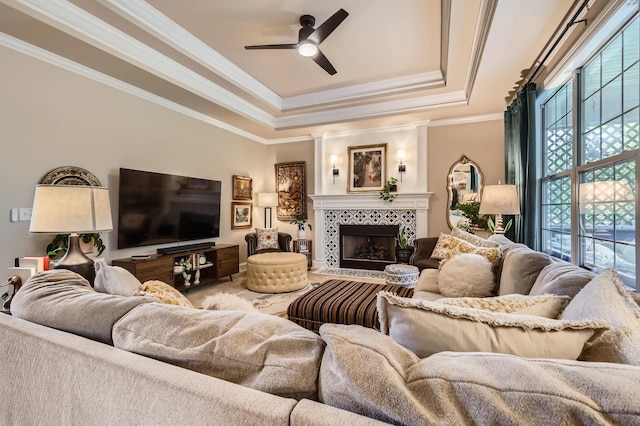 12723 Hawks Bill Ln, Plainfield, IL 60585 - living room featuring a tray ceiling, a ceiling fan, a fireplace, and crown molding
