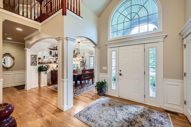12723 Hawks Bill Ln, Plainfield, IL 60585 - foyer entrance with ornate columns, arched walkways, a chandelier, a decorative wall, and light wood finished floors