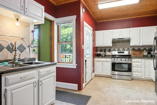 1100 N Hart St, Harvard, IL 60033 - kitchen with stainless steel gas range, under cabinet range hood, tasteful backsplash, dark countertops, and white cabinets