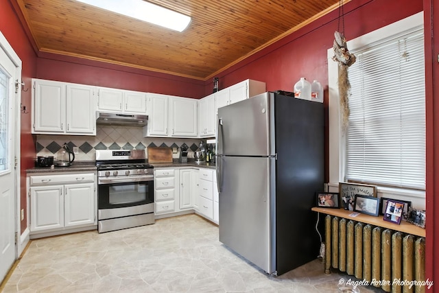 1100 N Hart St, Harvard, IL 60033 - kitchen with stainless steel appliances, under cabinet range hood, radiator, dark countertops, and white cabinetry
