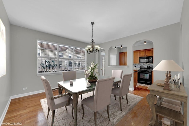 1697 Deer Pointe Dr, South Elgin, IL 60177 - dining space featuring light wood-style flooring, a chandelier, and arched walkways