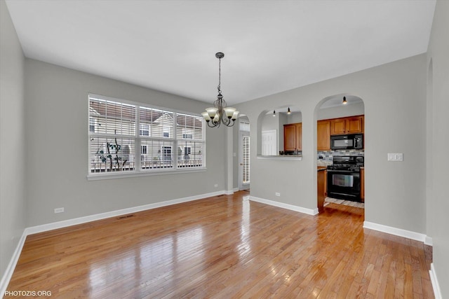 1697 Deer Pointe Dr, South Elgin, IL 60177 - unfurnished living room featuring light wood-style flooring, a chandelier, and arched walkways