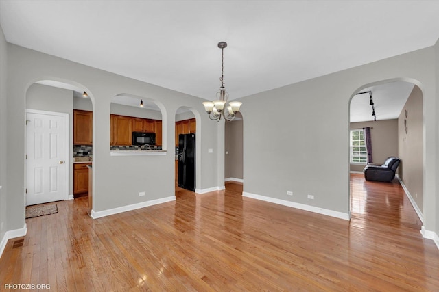 1697 Deer Pointe Dr, South Elgin, IL 60177 - unfurnished living room with light wood-style floors, arched walkways, and a chandelier
