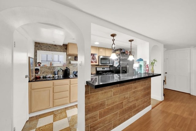 3617 W 63rd Pl, Chicago, IL 60629 - kitchen with stainless steel appliances, light brown cabinetry, dark countertops, arched walkways, and hanging light fixtures