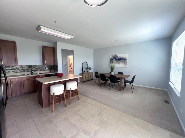 56 Veneto Ct, Streamwood, IL 60107 - kitchen featuring a breakfast bar area, light colored carpet, light countertops, a center island, and decorative backsplash