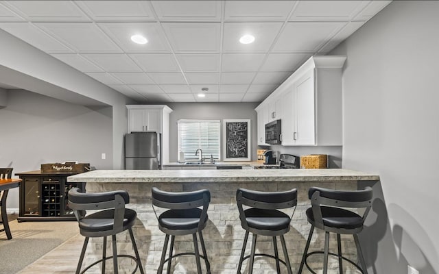 13052 Dunmoor Dr, Lemont, IL 60439 - kitchen with appliances with stainless steel finishes, white cabinetry, recessed lighting, a kitchen bar, and a peninsula