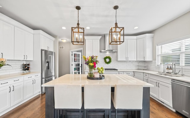 13052 Dunmoor Dr, Lemont, IL 60439 - kitchen featuring appliances with stainless steel finishes, wall chimney range hood, decorative backsplash, a center island, and white cabinets