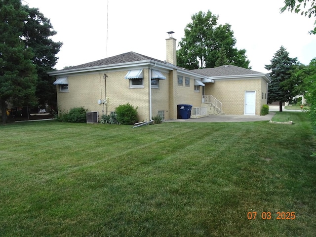 475 Courtesy Ln, Des Plaines, IL 60018 - back of property with a chimney, brick siding, and a yard