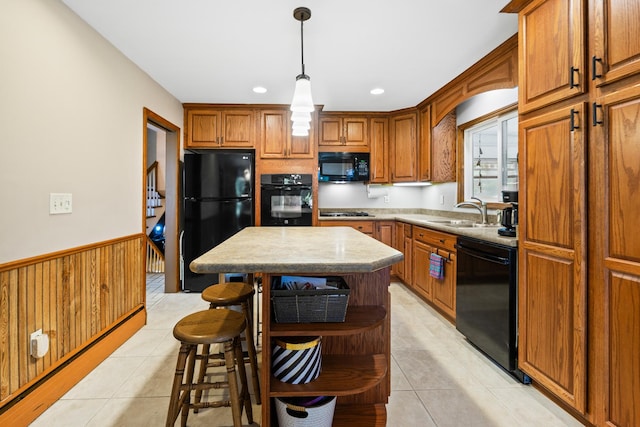 3717 W High St, Mchenry, IL 60050 - kitchen with black appliances, brown cabinetry, light tile patterned flooring, wainscoting, and decorative light fixtures