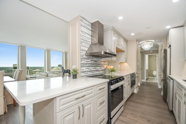 111 E Chestnut St Unit 4400J, Chicago, IL 60611 - kitchen with wall chimney range hood, appliances with stainless steel finishes, light countertops, light wood-type flooring, and recessed lighting