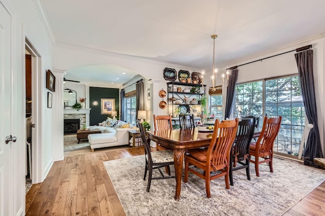 12740 Hawks Bill Ln, Plainfield, IL 60585 - dining area featuring arched walkways, crown molding, hardwood / wood-style floors, a stone fireplace, and a chandelier