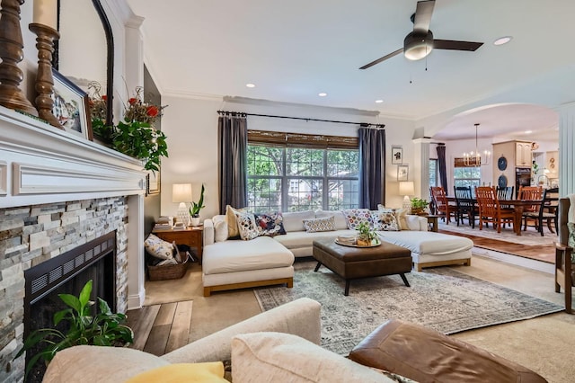 12740 Hawks Bill Ln, Plainfield, IL 60585 - living area with arched walkways, ceiling fan, a stone fireplace, a chandelier, and ornamental molding