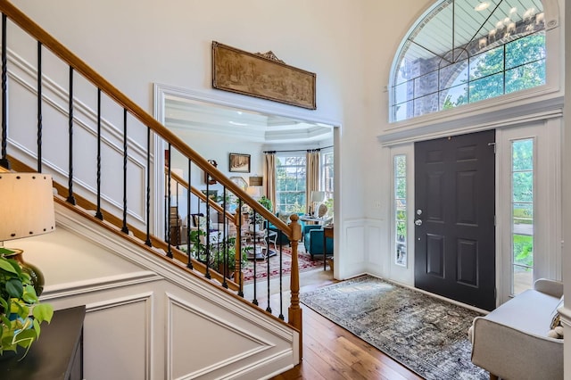 12740 Hawks Bill Ln, Plainfield, IL 60585 - foyer entrance featuring wood-type flooring, stairs, a wainscoted wall, a decorative wall, and a high ceiling