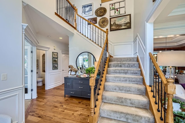 12740 Hawks Bill Ln, Plainfield, IL 60585 - stairs with wood finished floors, a decorative wall, crown molding, and wainscoting
