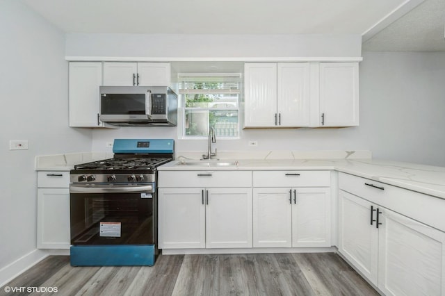 6545 S Hamilton Ave, Chicago, IL 60636 - kitchen with stainless steel appliances, light wood-style flooring, white cabinetry, and light stone countertops