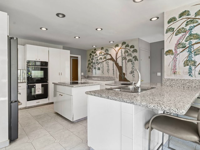 922 S School St, Mount Prospect, IL 60056 - kitchen featuring black appliances, a peninsula, recessed lighting, white cabinetry, and a kitchen breakfast bar